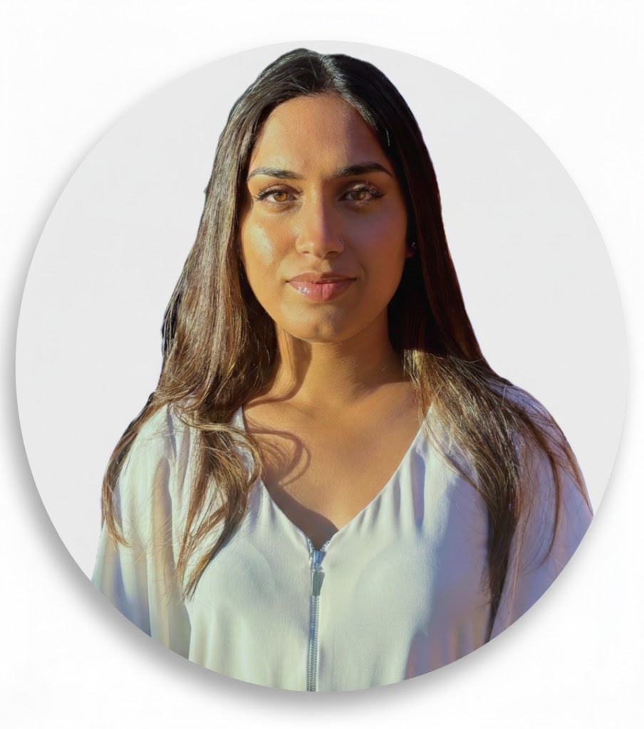 A close-up portrait of a woman with long dark hair, wearing a white blouse and looking directly at the camera.